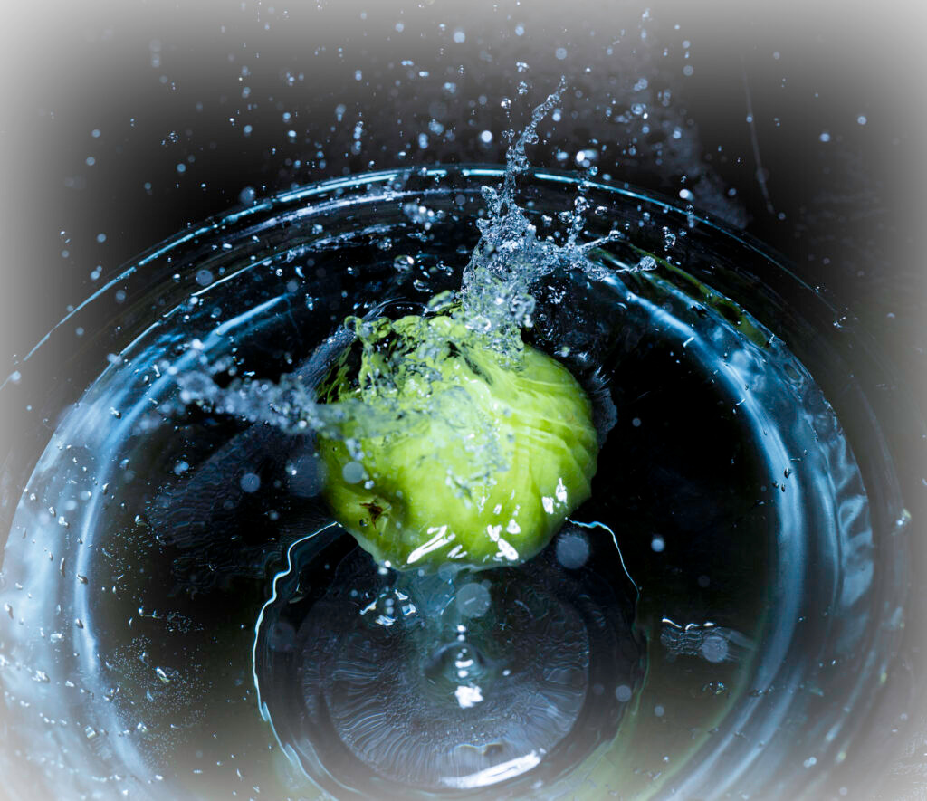 Green apple splashing into water explosive droplets blue background high speed photography fine art by Hadi Baradaran ArtQuestor