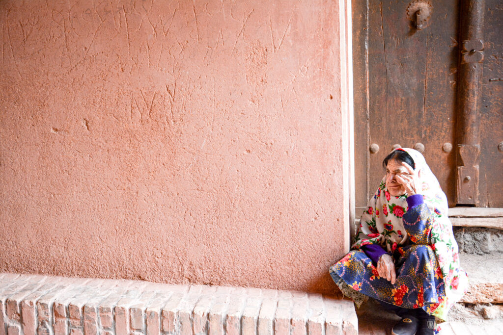 elderly woman traditional colorful floral chador Abyaneh ancient village Iran fine art travel photography by Hadi Baradaran ArtQuestor